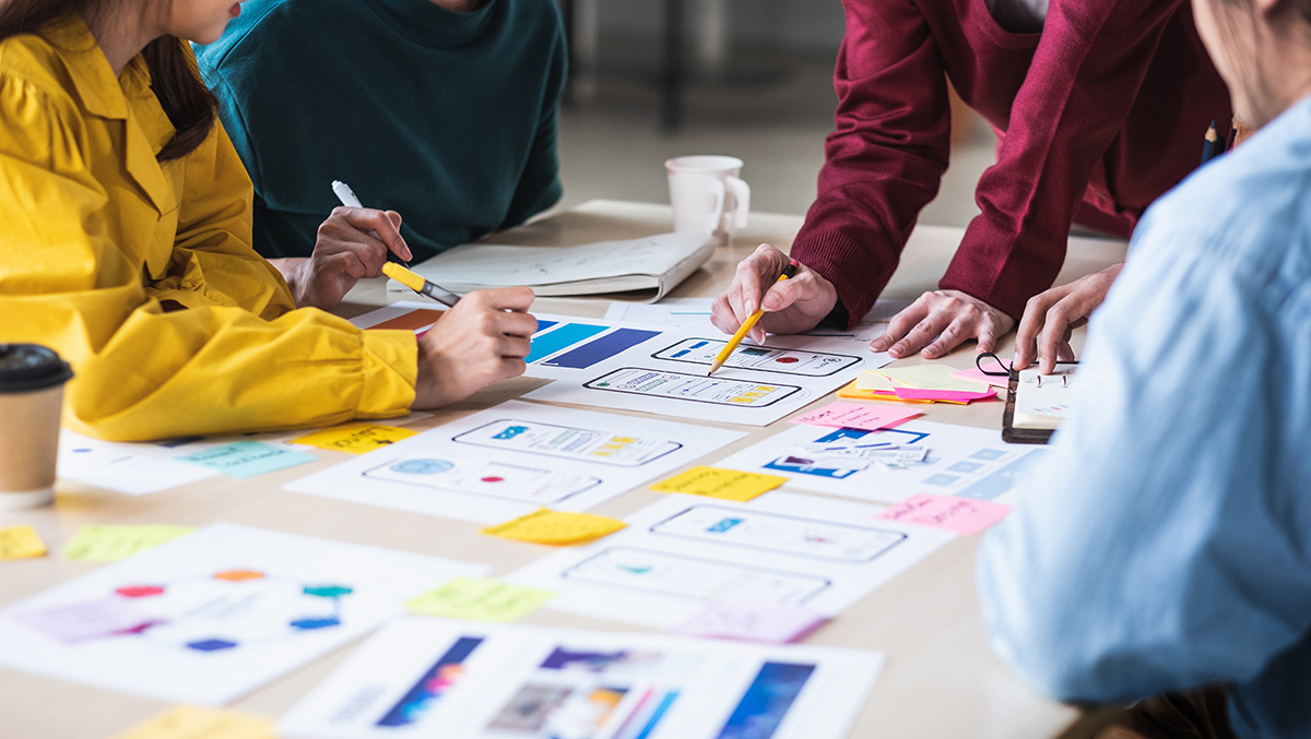 Close,Up,Ux,Developer,And,Ui,Designer,Brainstorming,About,Mobile Close up ux developer and ui designer brainstorming about mobile app interface wireframe design on table with customer breif and color code at modern office.Creative digital development agency